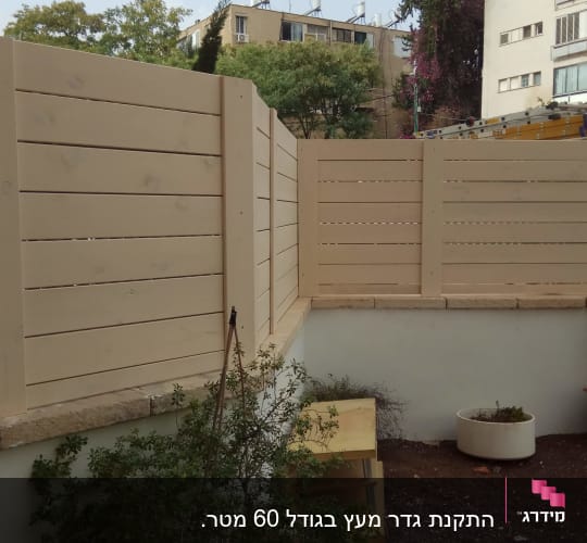 גדר עץ בהירה עם עציצים בגינה